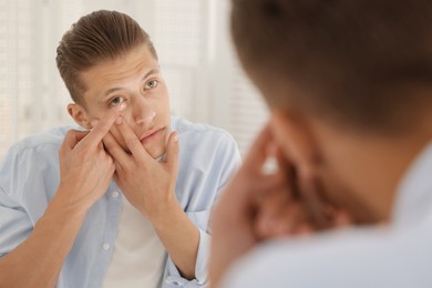 Photo of Man putting in contact lens near mirror at home