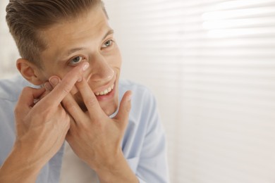 Photo of Man putting in contact lens at home. Space for text