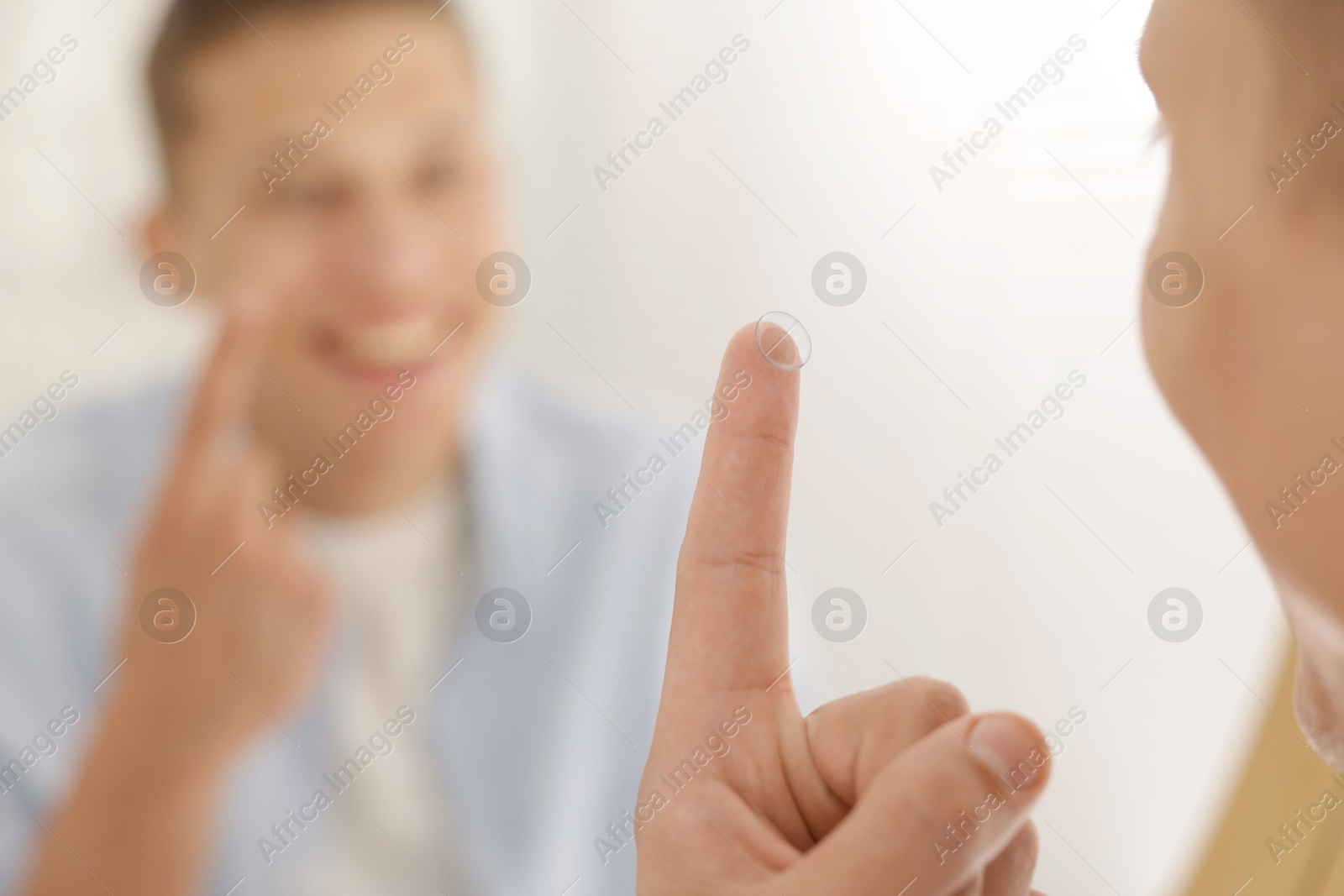 Man with contact lens near mirror at home, selective focus Photo of Man with contact lens near mirror at home, selective focus