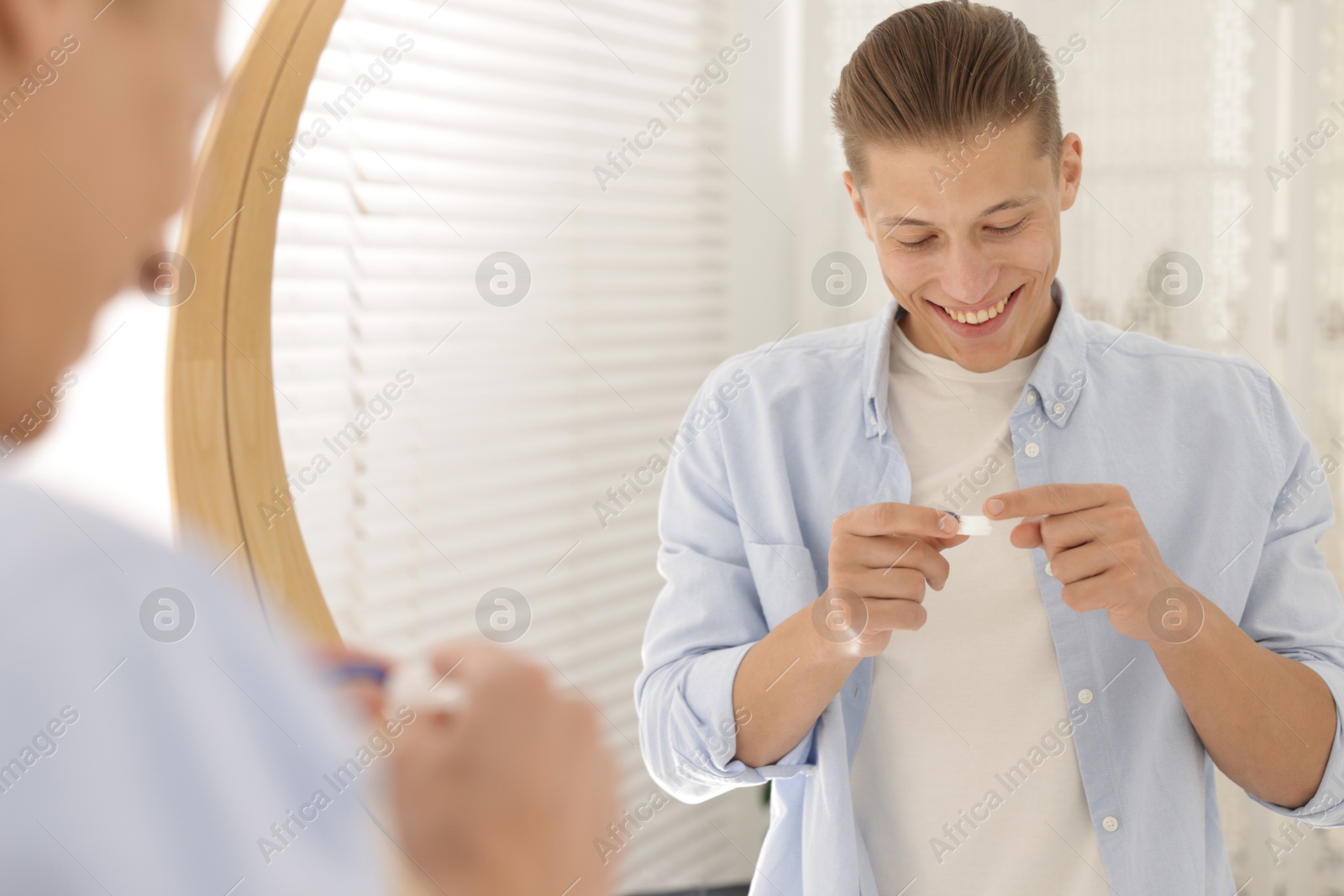 Man with case of contact lenses near mirror at home Photo of Man with case of contact lenses near mirror at home