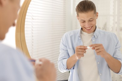 Photo of Man with case of contact lenses near mirror at home