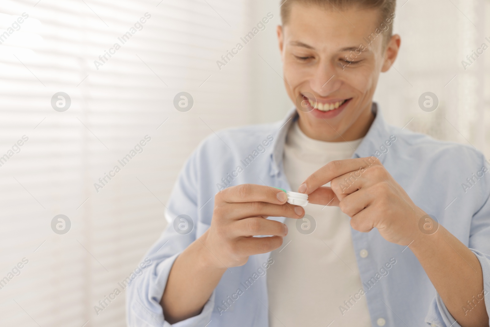 Man with case of contact lenses at home. Space for text Photo of Man with case of contact lenses at home. Space for text
