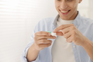Photo of Man with case of contact lenses at home, closeup. Space for text
