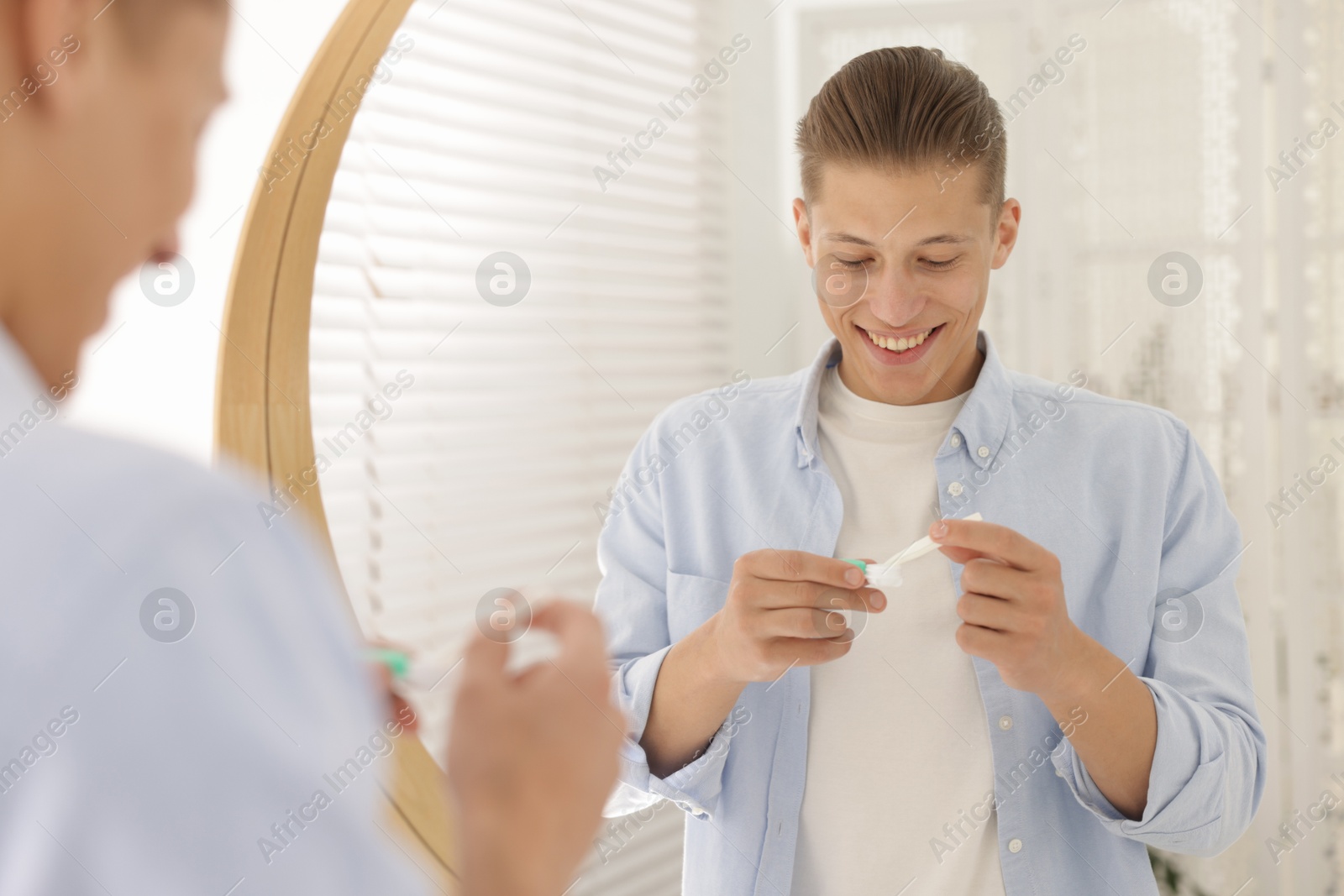 Photo of Man taking contact lens out of case near mirror at home