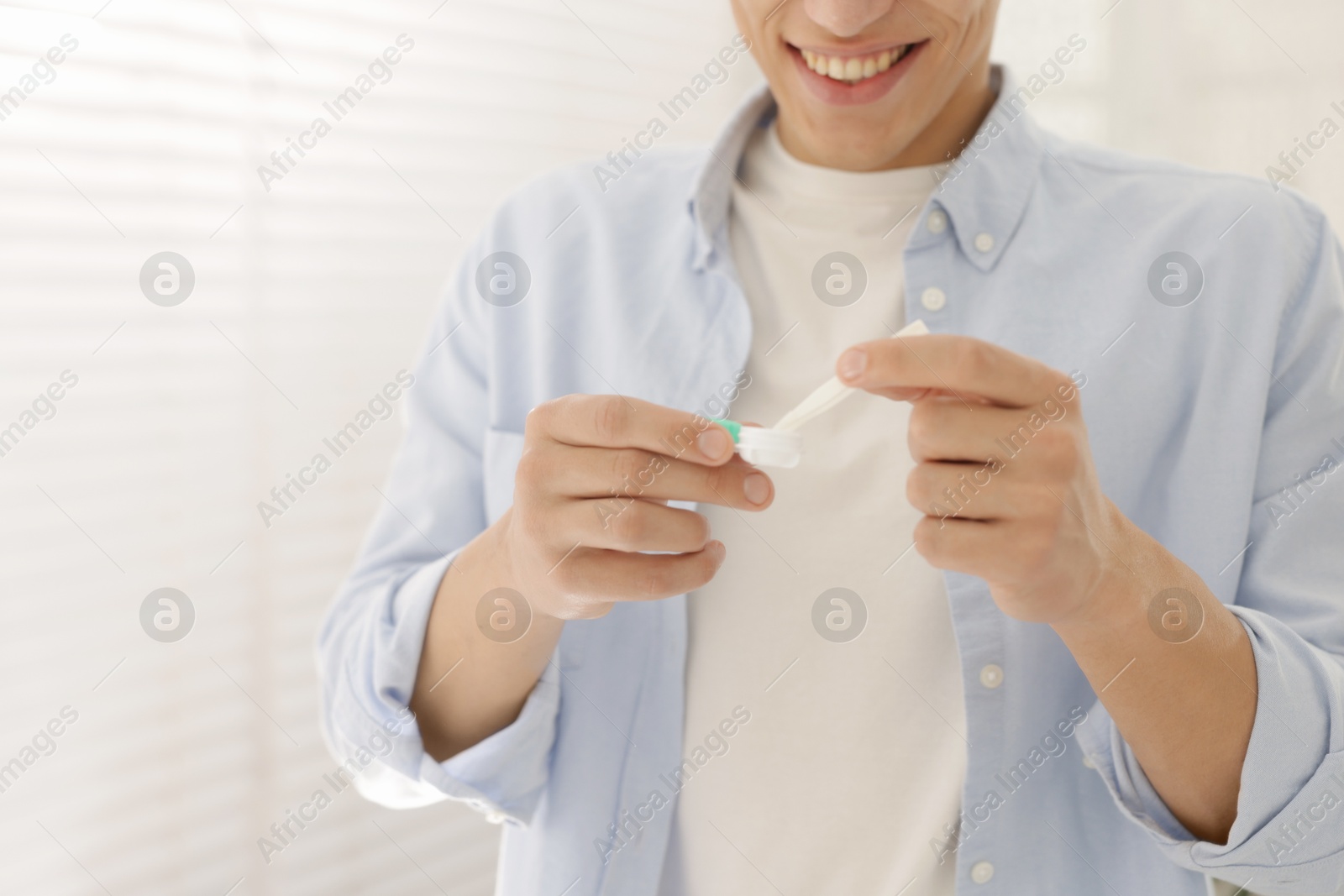 Man taking contact lens out of case at home, closeup Photo of Man taking contact lens out of case at home, closeup
