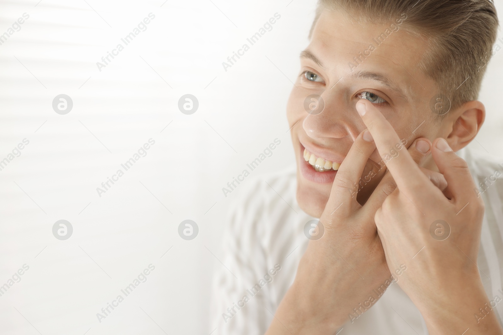 Man putting in contact lens at home. Space for text Photo of Man putting in contact lens at home. Space for text