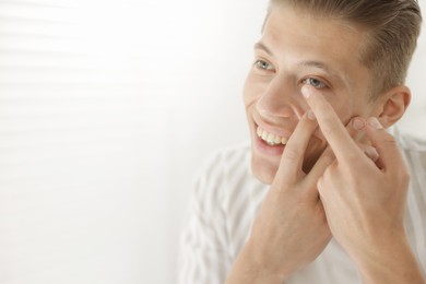 Photo of Man putting in contact lens at home. Space for text