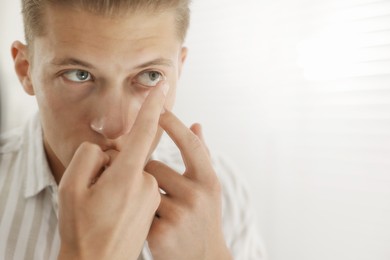 Photo of Man putting in contact lens at home, closeup. Space for text