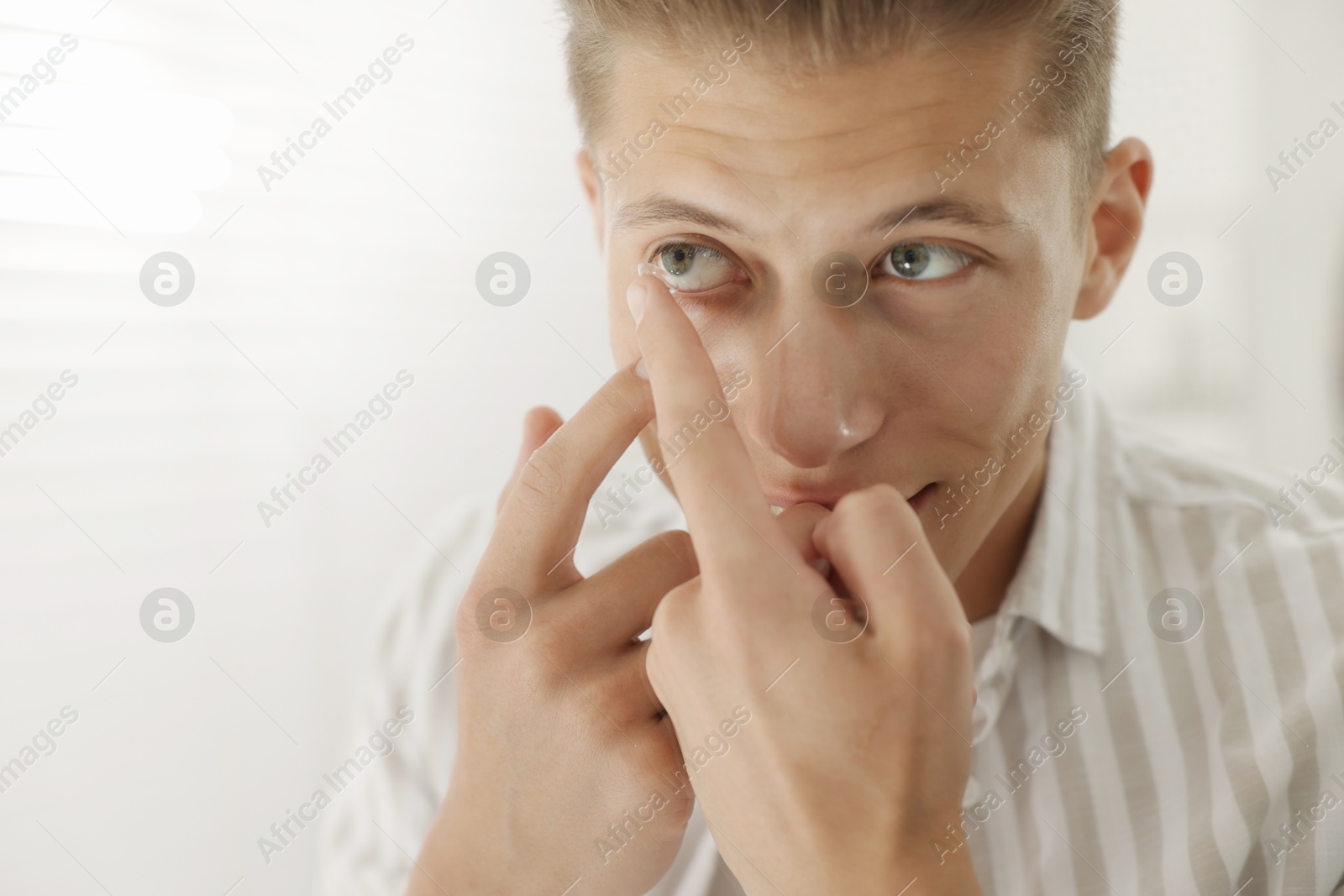 Man putting in contact lens at home, closeup Photo of Man putting in contact lens at home, closeup