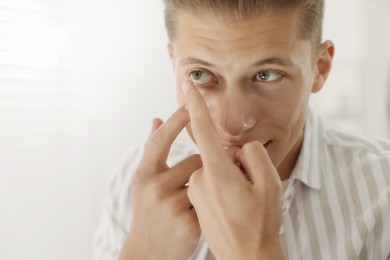 Photo of Man putting in contact lens at home, closeup