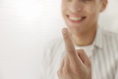Photo of Man with contact lens at home, closeup. Space for text