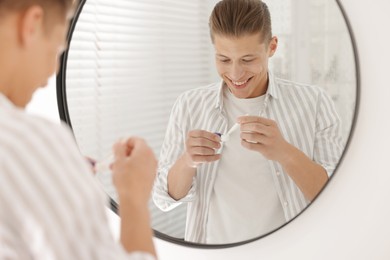 Photo of Man taking contact lens out of case near mirror at home