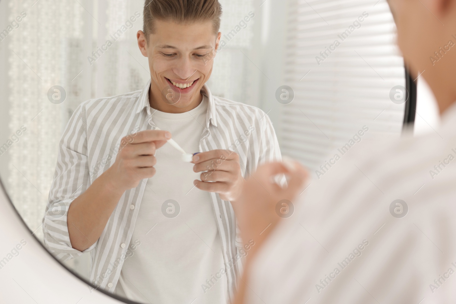 Photo of Man taking contact lens out of case near mirror at home
