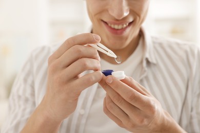 Photo of Man taking contact lens out of case at home, closeup