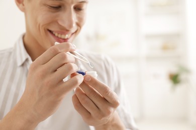 Photo of Man taking contact lens out of case at home, closeup. Space for text