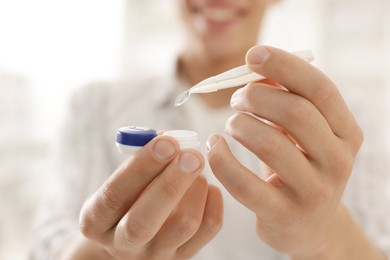 Photo of Man taking contact lens out of case at home, closeup