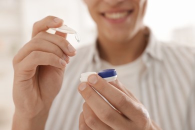 Photo of Man taking contact lens out of case at home, closeup