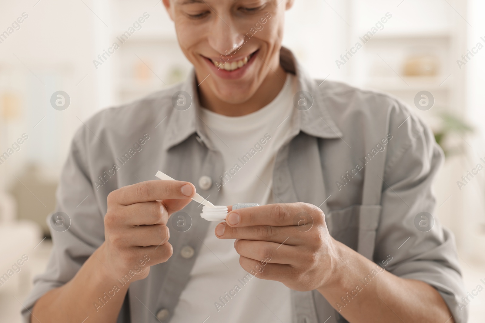 Man taking contact lens out of case at home, closeup Photo of Man taking contact lens out of case at home, closeup