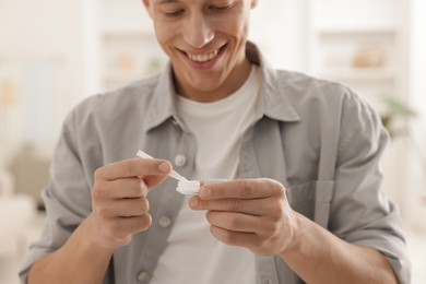 Photo of Man taking contact lens out of case at home, closeup