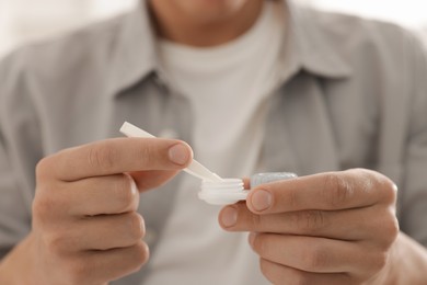 Photo of Man taking contact lens out of case at home, closeup