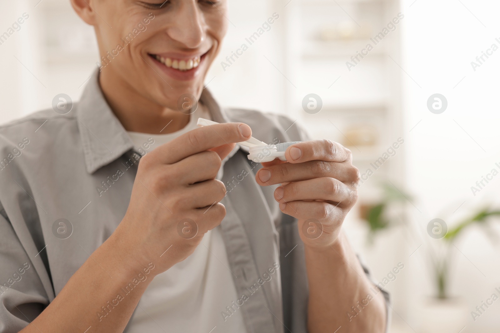Man taking contact lens out of case at home, closeup Photo of Man taking contact lens out of case at home, closeup