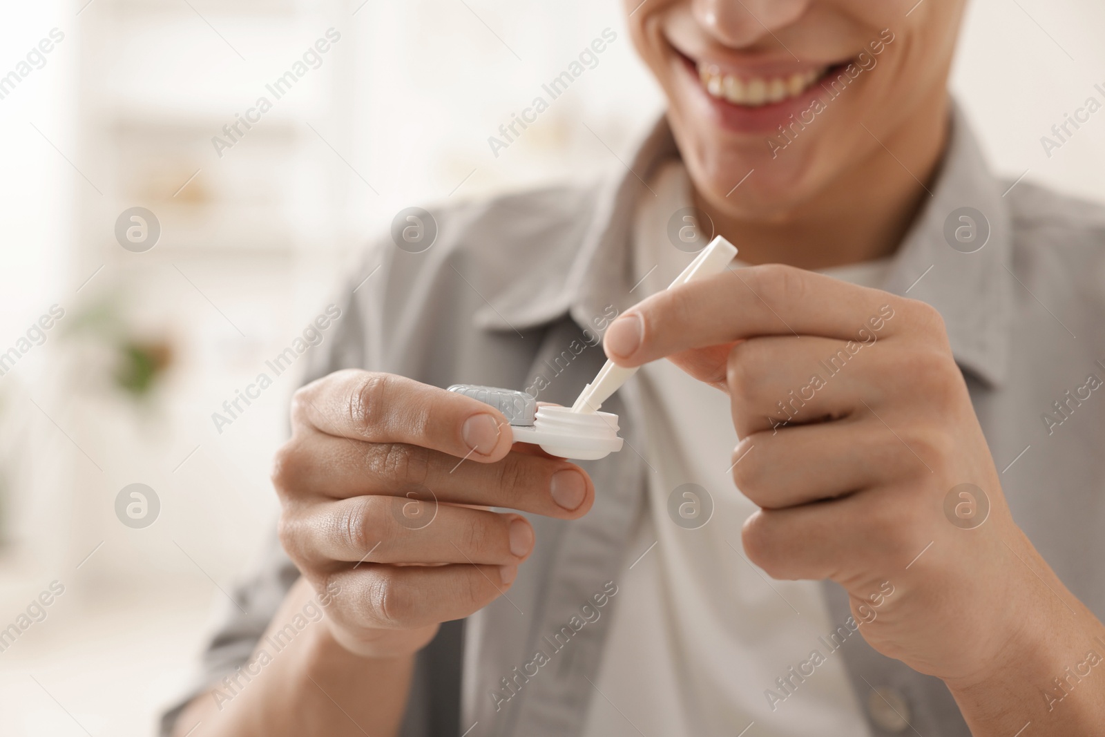Man taking contact lens out of case at home, closeup Photo of Man taking contact lens out of case at home, closeup
