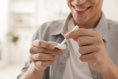 Photo of Man taking contact lens out of case at home, closeup