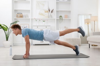 Photo of Man doing plank exercise at home. Sport and healthy lifestyle