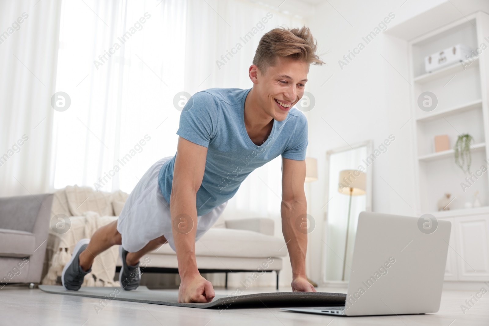 Man doing plank exercise during online class with coach at home. Sport and healthy lifestyle Photo of Man doing plank exercise during online class with coach at home. Sport and healthy lifestyle