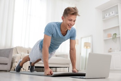 Photo of Man doing plank exercise during online class with coach at home. Sport and healthy lifestyle