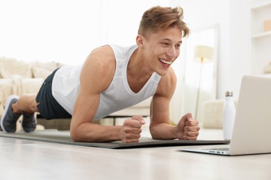 Photo of Man doing plank exercise during online class with coach at home. Sport and healthy lifestyle