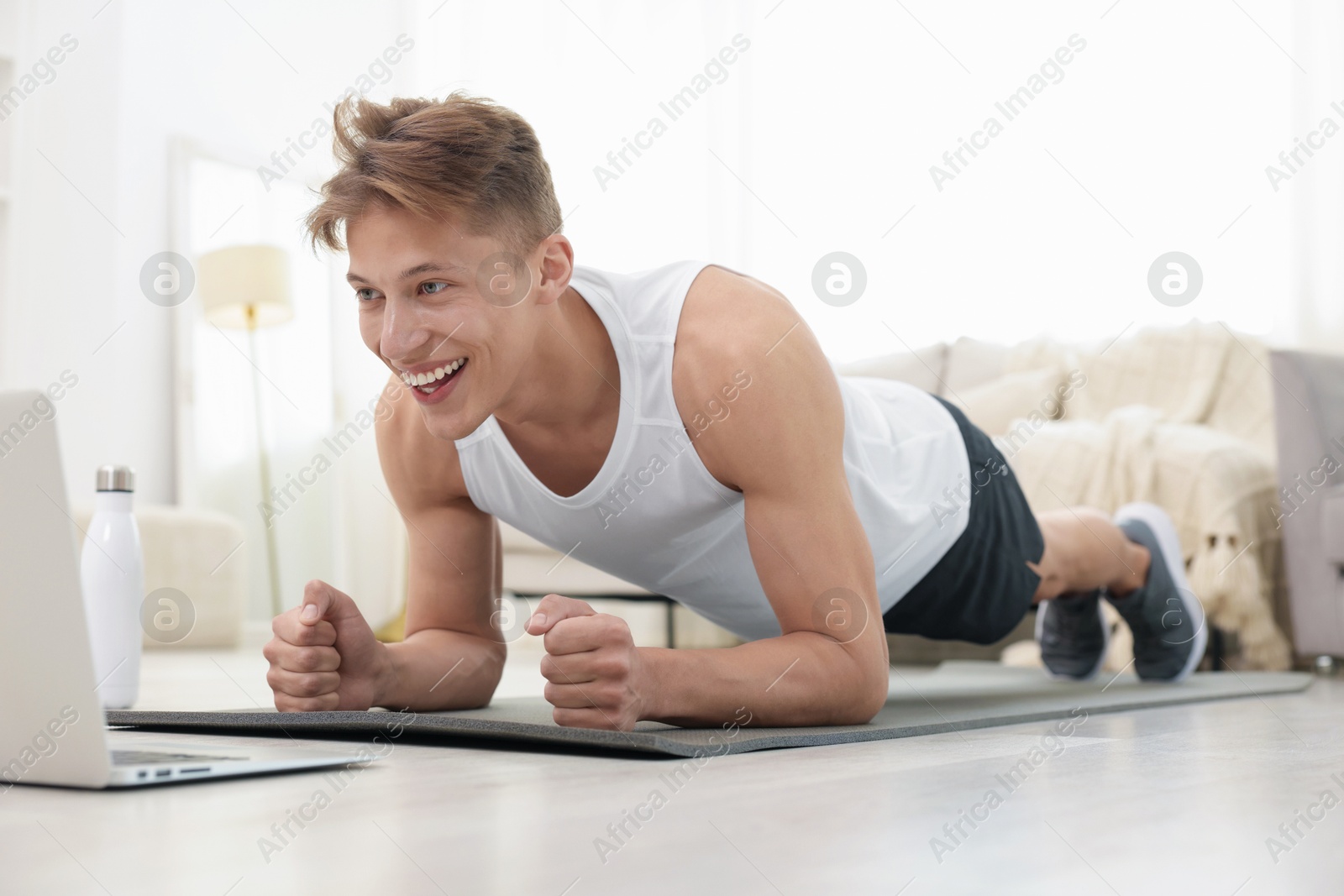 Man doing plank exercise during online class with coach at home. Sport and healthy lifestyle Photo of Man doing plank exercise during online class with coach at home. Sport and healthy lifestyle
