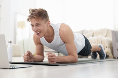 Photo of Man doing plank exercise during online class with coach at home. Sport and healthy lifestyle
