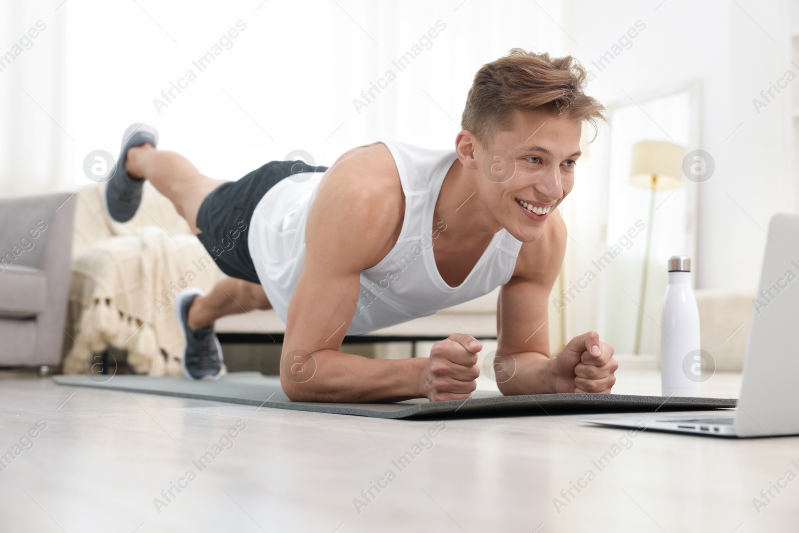 Man doing plank exercise during online class with coach at home. Sport and healthy lifestyle Photo of Man doing plank exercise during online class with coach at home. Sport and healthy lifestyle