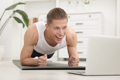 Photo of Man doing plank exercise during online class with coach at home. Sport and healthy lifestyle