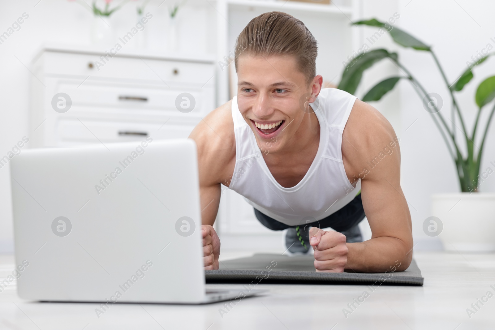 Man doing plank exercise during online class with coach at home. Sport and healthy lifestyle Photo of Man doing plank exercise during online class with coach at home. Sport and healthy lifestyle