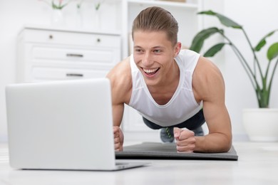 Photo of Man doing plank exercise during online class with coach at home. Sport and healthy lifestyle