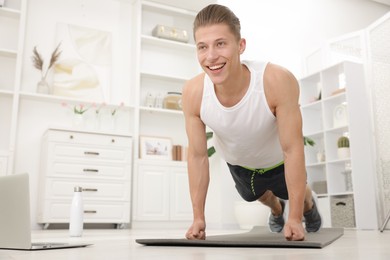 Photo of Man doing plank exercise during online class with coach at home. Sport and healthy lifestyle