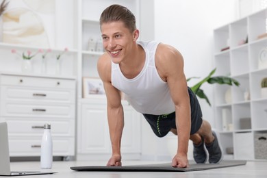 Photo of Man doing plank exercise during online class with coach at home. Sport and healthy lifestyle
