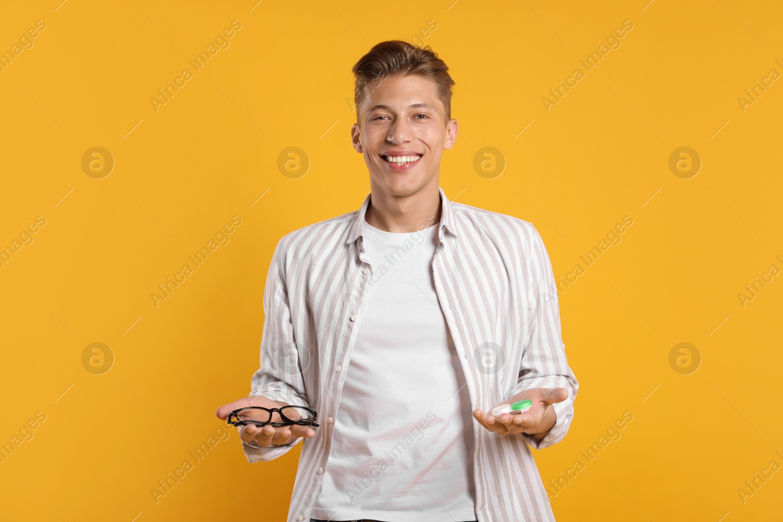 Man choosing between glasses and contact lenses on yellow background Photo of Man choosing between glasses and contact lenses on yellow background