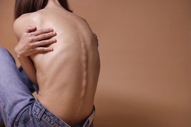 Photo of Woman suffering from anorexia on dark beige background, closeup. Space for text