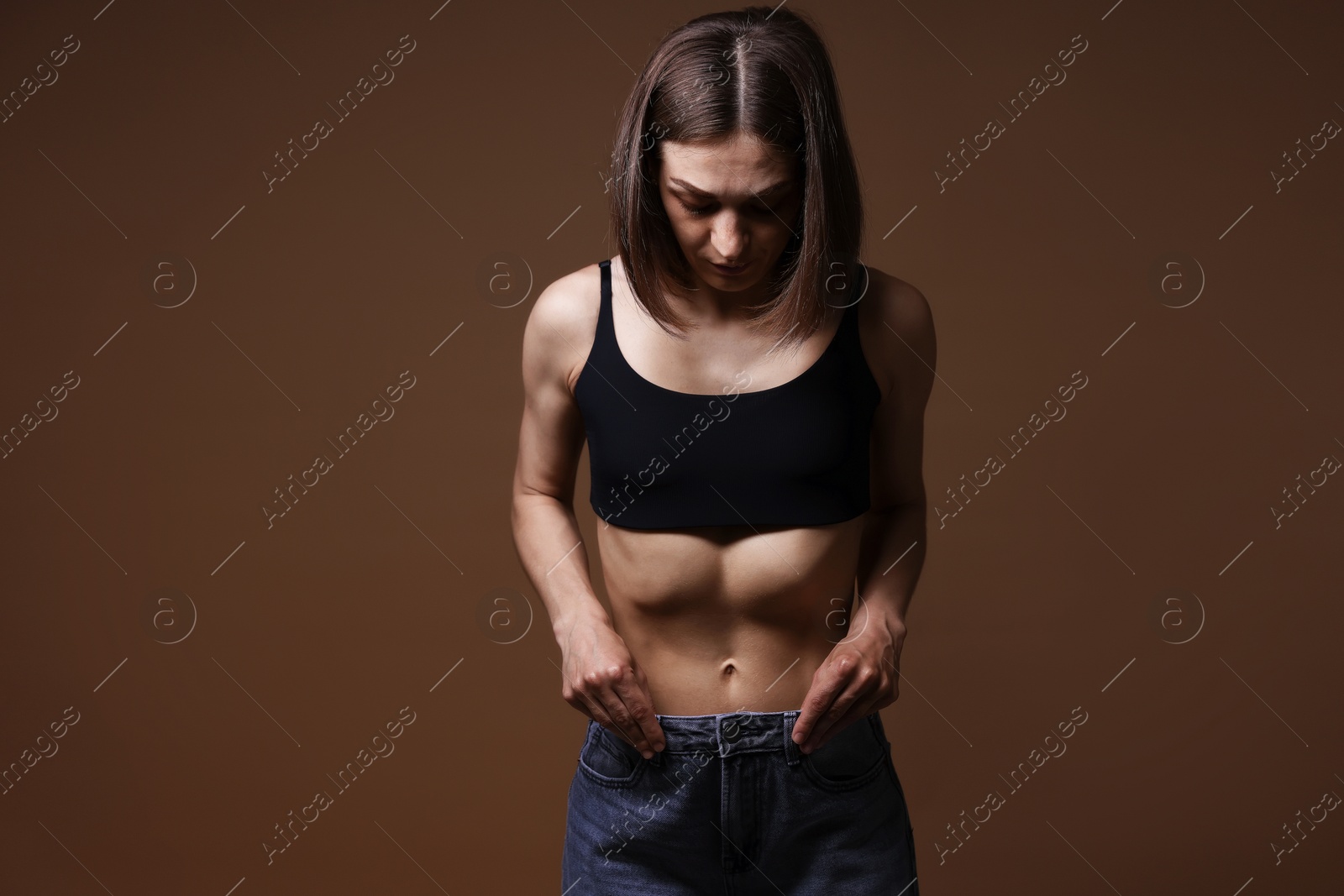 Woman suffering from anorexia on brown background Photo of Woman suffering from anorexia on brown background