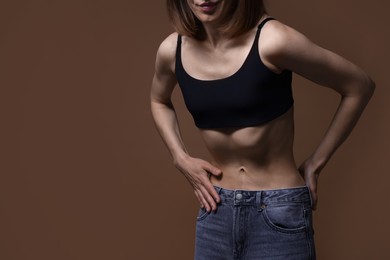 Photo of Woman suffering from anorexia on brown background, closeup. Space for text