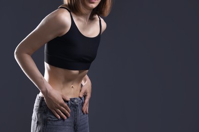 Photo of Woman suffering from anorexia on grey background, closeup. Space for text