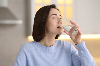 Photo of Young woman drinking water from at home