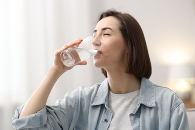 Photo of Young woman drinking water from at home