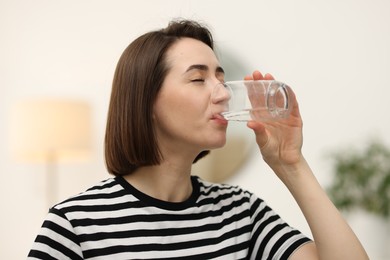 Photo of Young woman drinking water from at home