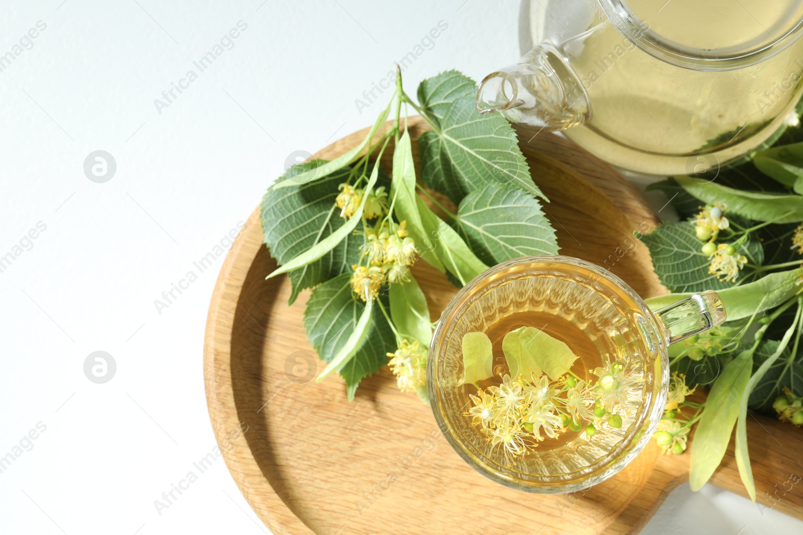 Tasty linden tea, leaves and flowers on light table, flat lay Photo of Tasty linden tea, leaves and flowers on light table, flat lay