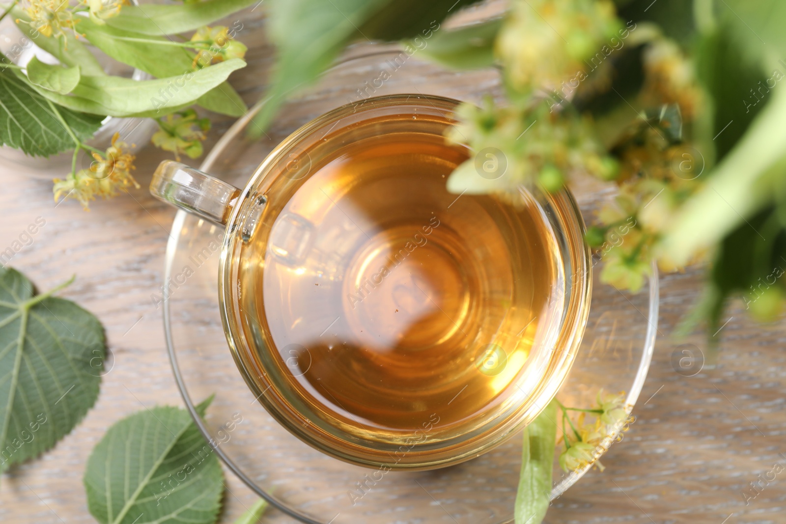 Tasty linden tea in cup, leaves and flowers on wooden table, flat lay Photo of Tasty linden tea in cup, leaves and flowers on wooden table, flat lay
