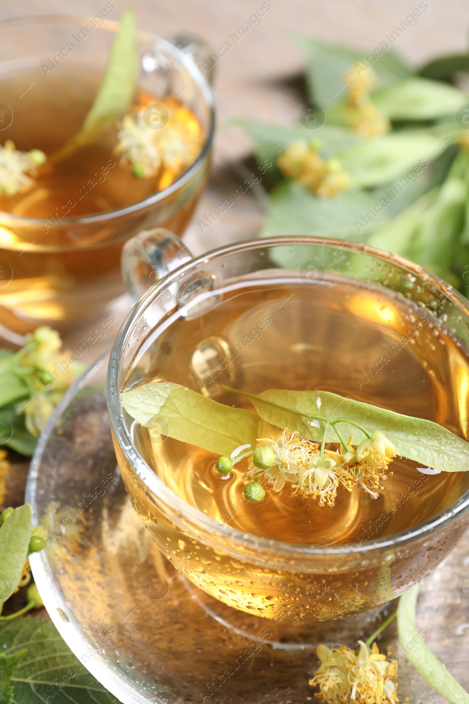 Tasty linden tea, leaves and flowers on table, closeup Photo of Tasty linden tea, leaves and flowers on table, closeup